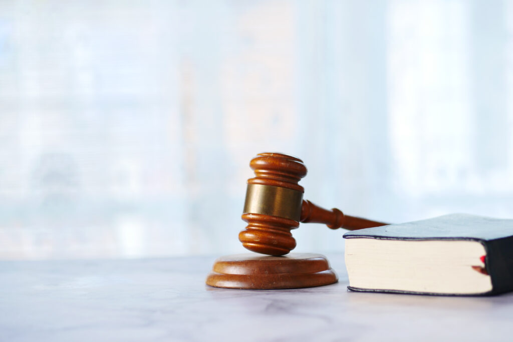 A wooden gavel resting beside a law book on a table, symbolizing justice, authority, and decision making